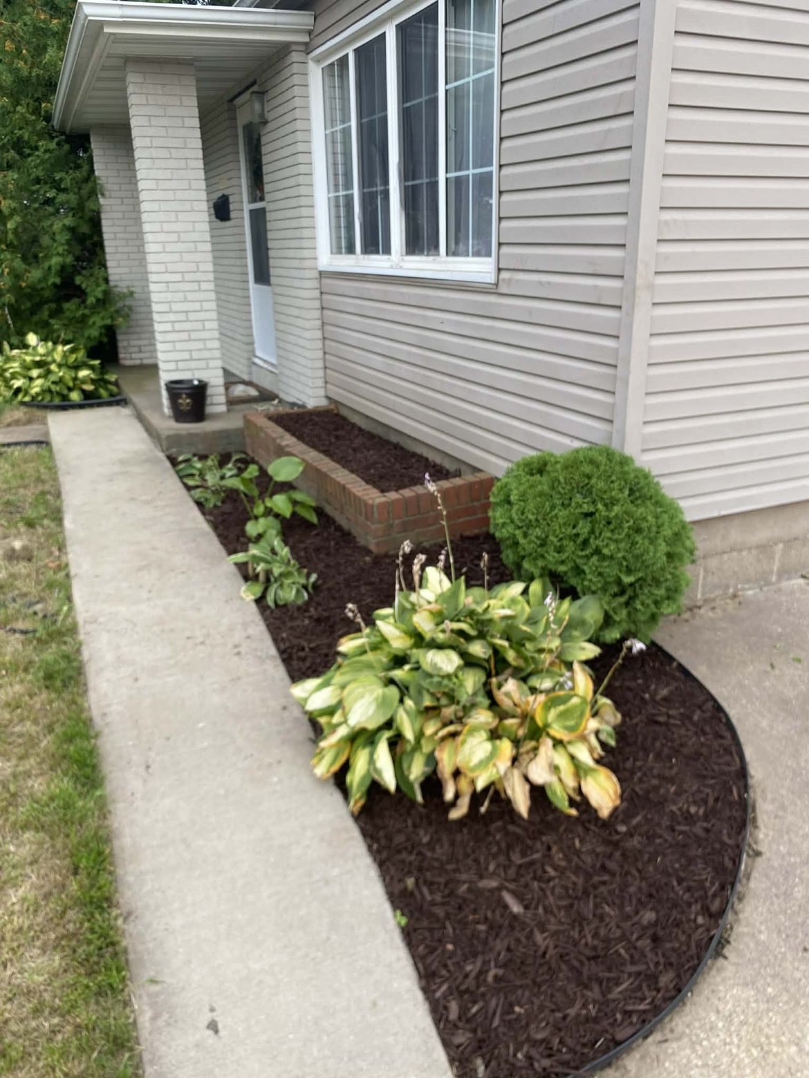 Fresh mulch beds and trimmed shrubs along a home's walkway